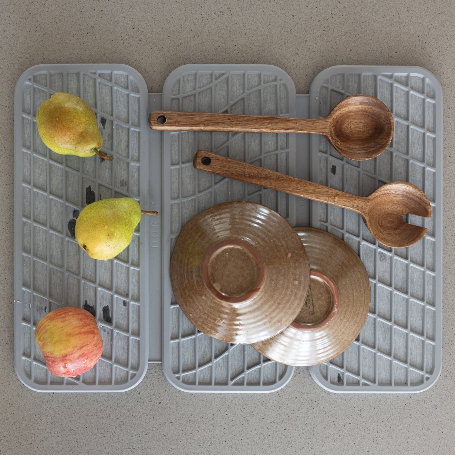 light grey dish mat with wooden spoons and fruit drying